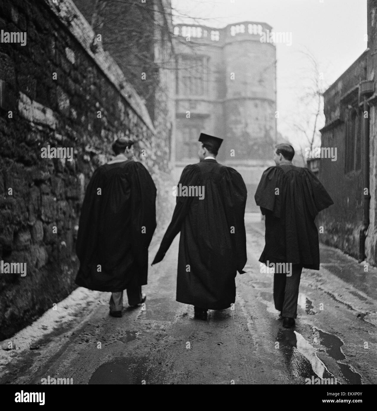 Étudiant de l'Université d'Oxford marche à travers l'une des étroites ruelles de la ville portant des robes de l'université. Vers 1950. Banque D'Images