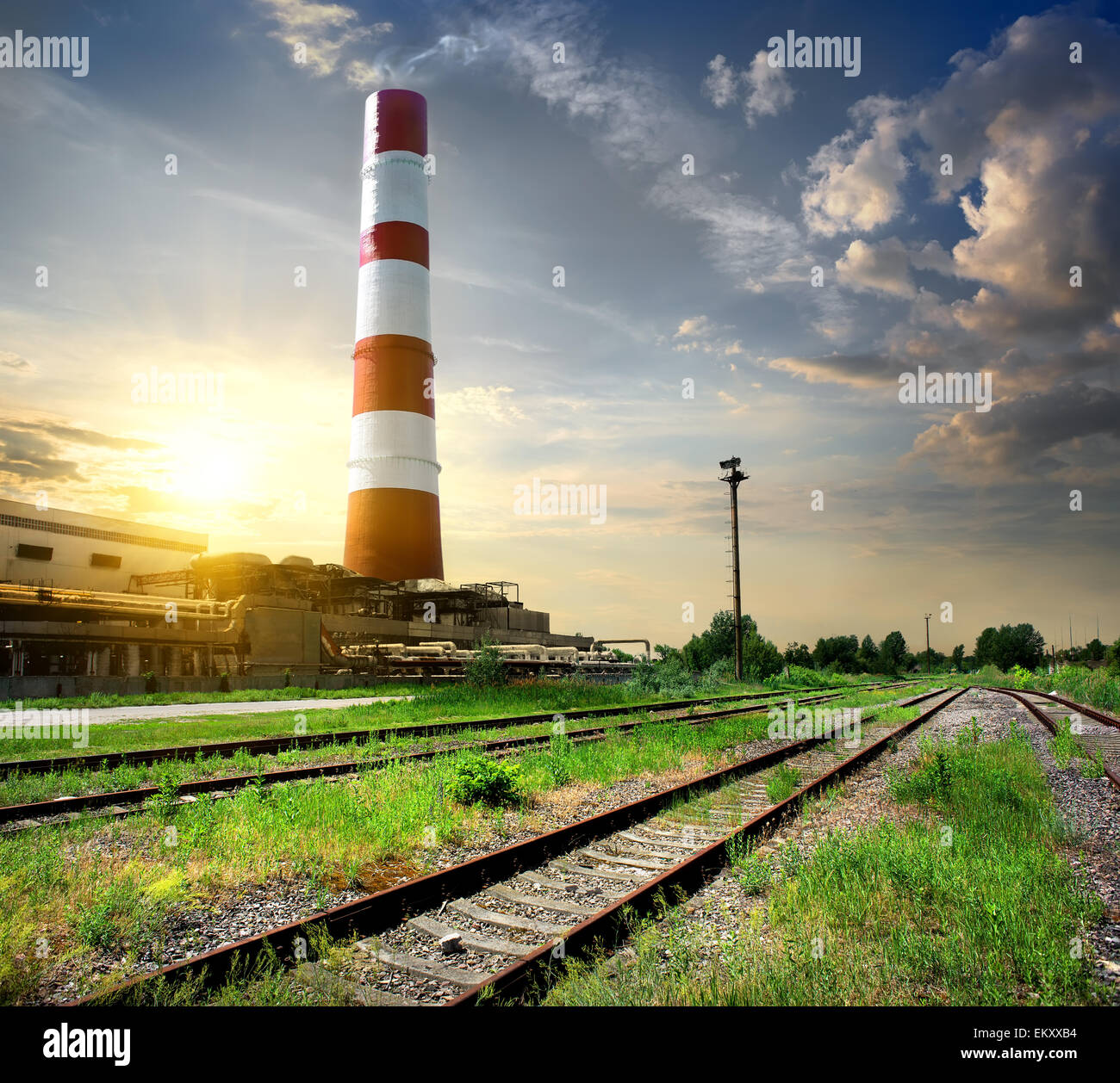 Railroad et tube industriel sous ciel nuageux Banque D'Images