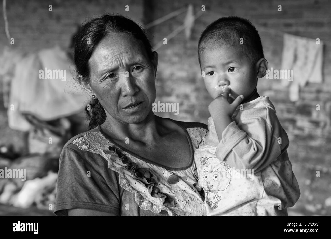 Une femme tenant un jeune enfant ; la Chine Yunnan Ruili Banque D'Images