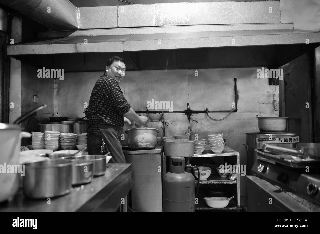 Un homme travaillant dans une cuisine ; la Chine Yunnan Ruili Banque D'Images