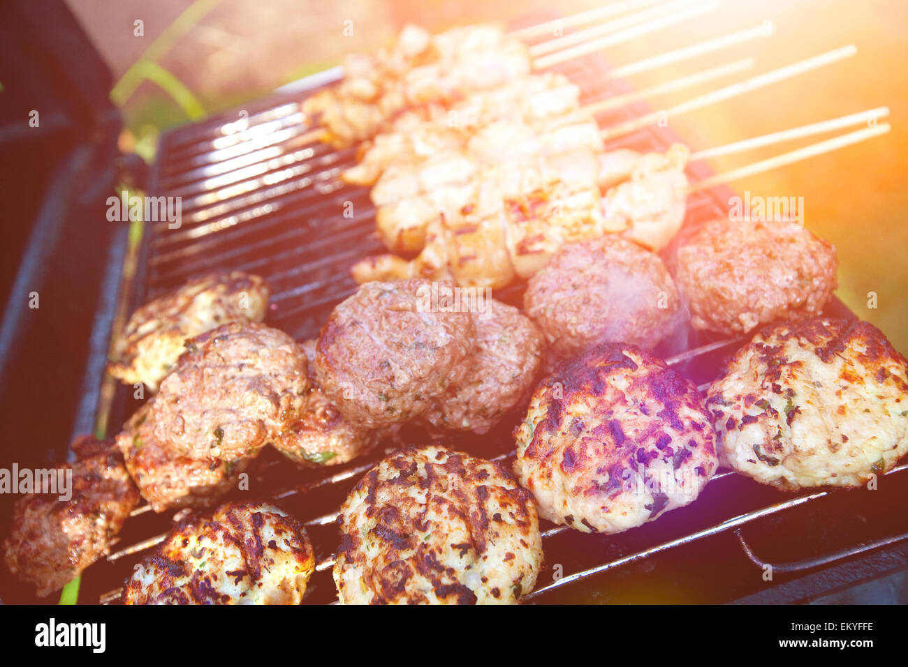 Des hamburgers et des viandes grillées sur le barbecue satays prêt pour les repas en plein air d'été Banque D'Images