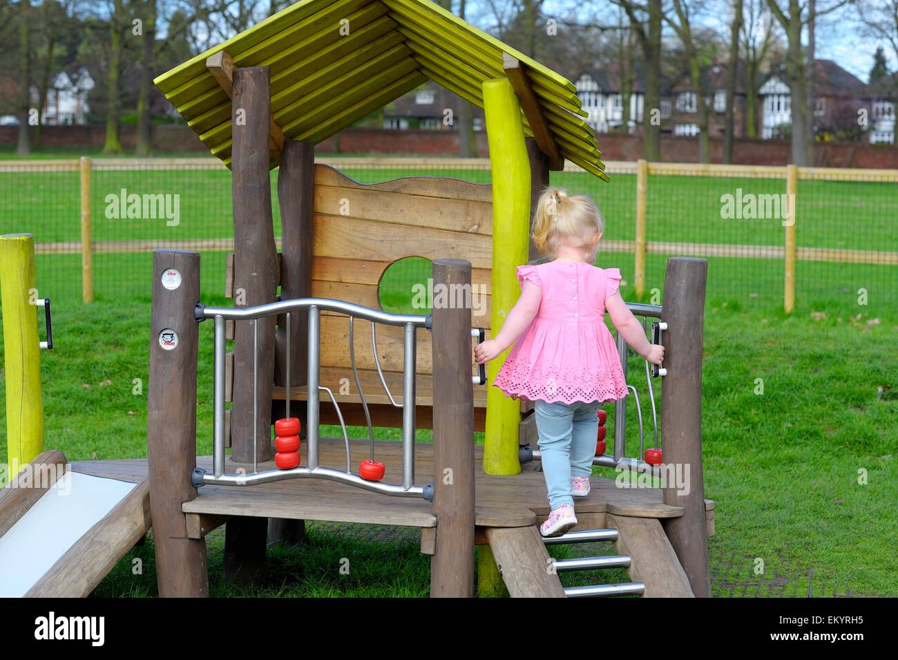 Un enfant de 2 ans bébé fille grimper les échelles sur un parc slide Wollaton park, Angleterre, Royaume-Uni Banque D'Images