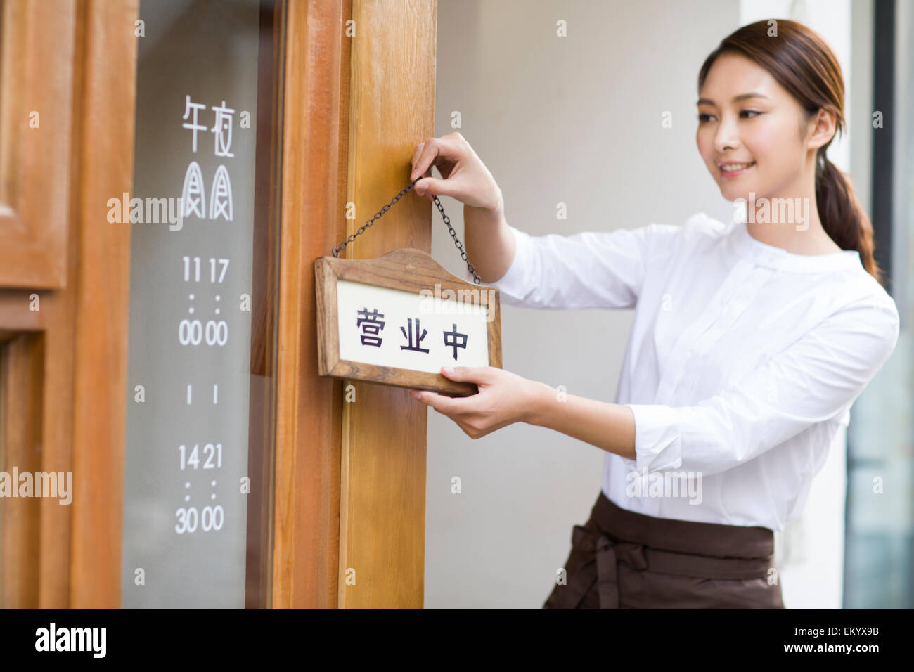 Jeune serveuse avec open sign in restaurant porte Banque D'Images