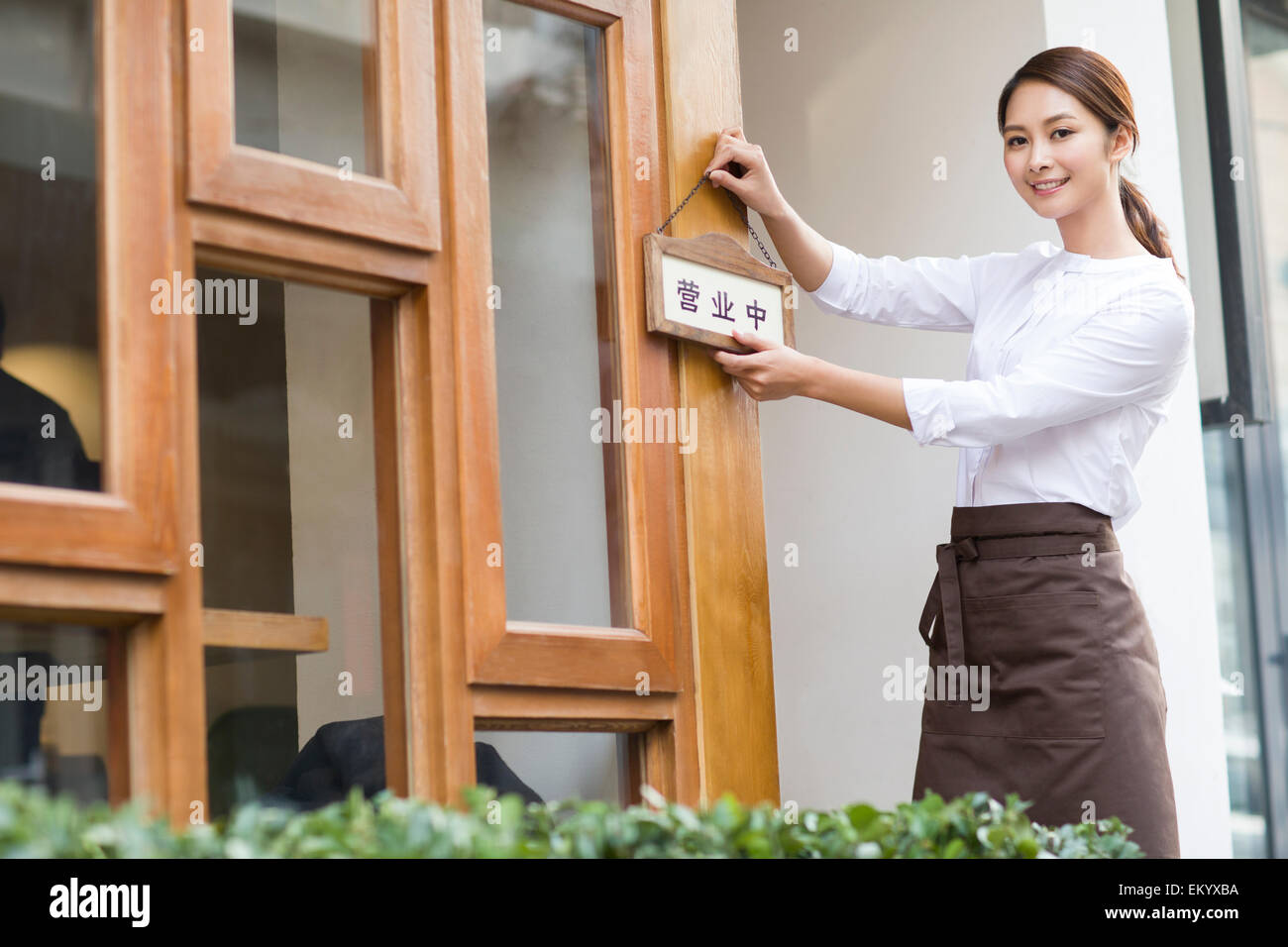 Jeune serveuse avec open sign in restaurant porte Banque D'Images