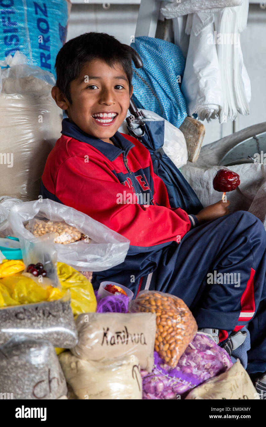 Pérou, Cusco, Marché de San Pedro. Jeune garçon mangeant une pomme confite. Banque D'Images
