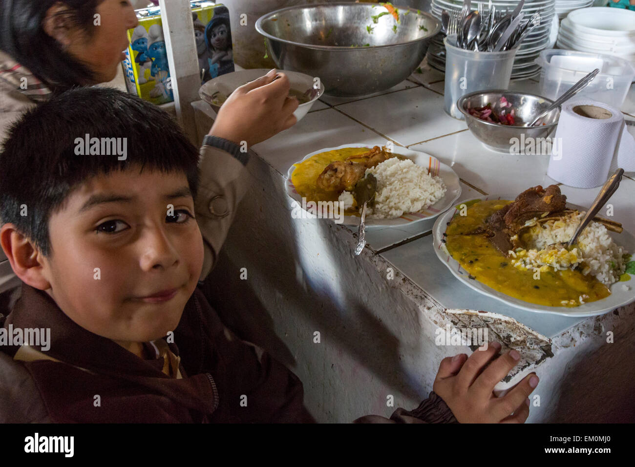 Pérou, Cusco, Marché de San Pedro. Jeune garçon avec son repas de riz, de Bœuf et de sauce dans le Food Court dans le quartier du marché. Banque D'Images