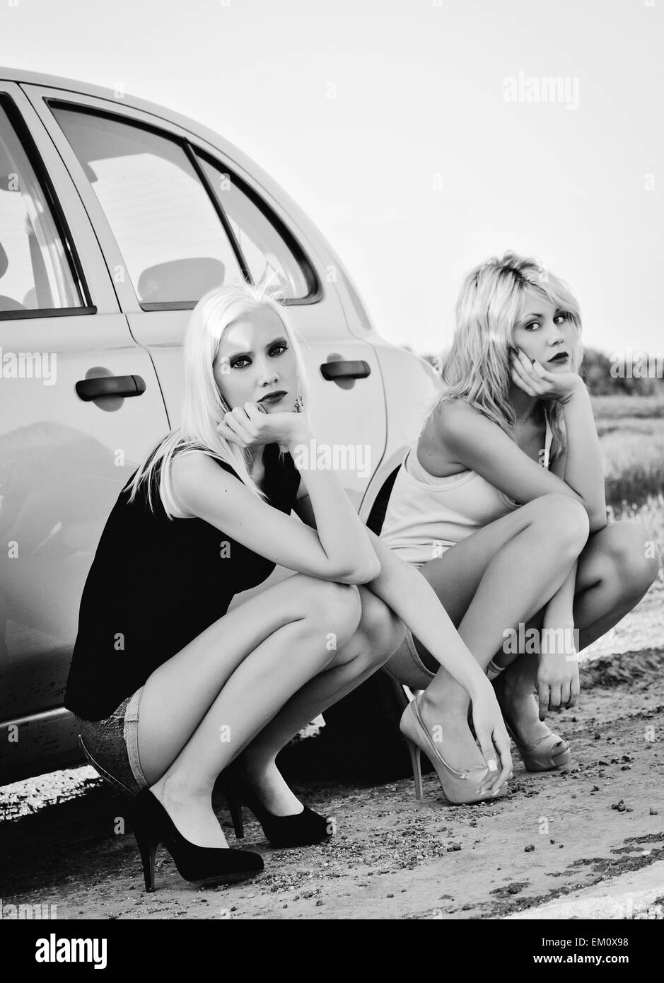 Deux belles blondes assis près de voiture cassée et l'attente de l'aide Banque D'Images