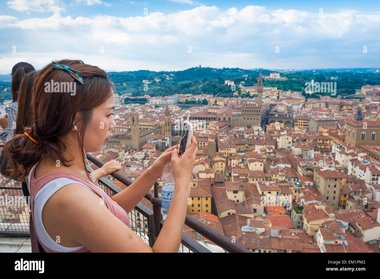 Le tourisme asiatique, vue d'un touriste japonais sur la plate-forme d'observation de la cathédrale de Florence dôme en prenant une photo avec un smartphone de la ville ci-dessous Banque D'Images