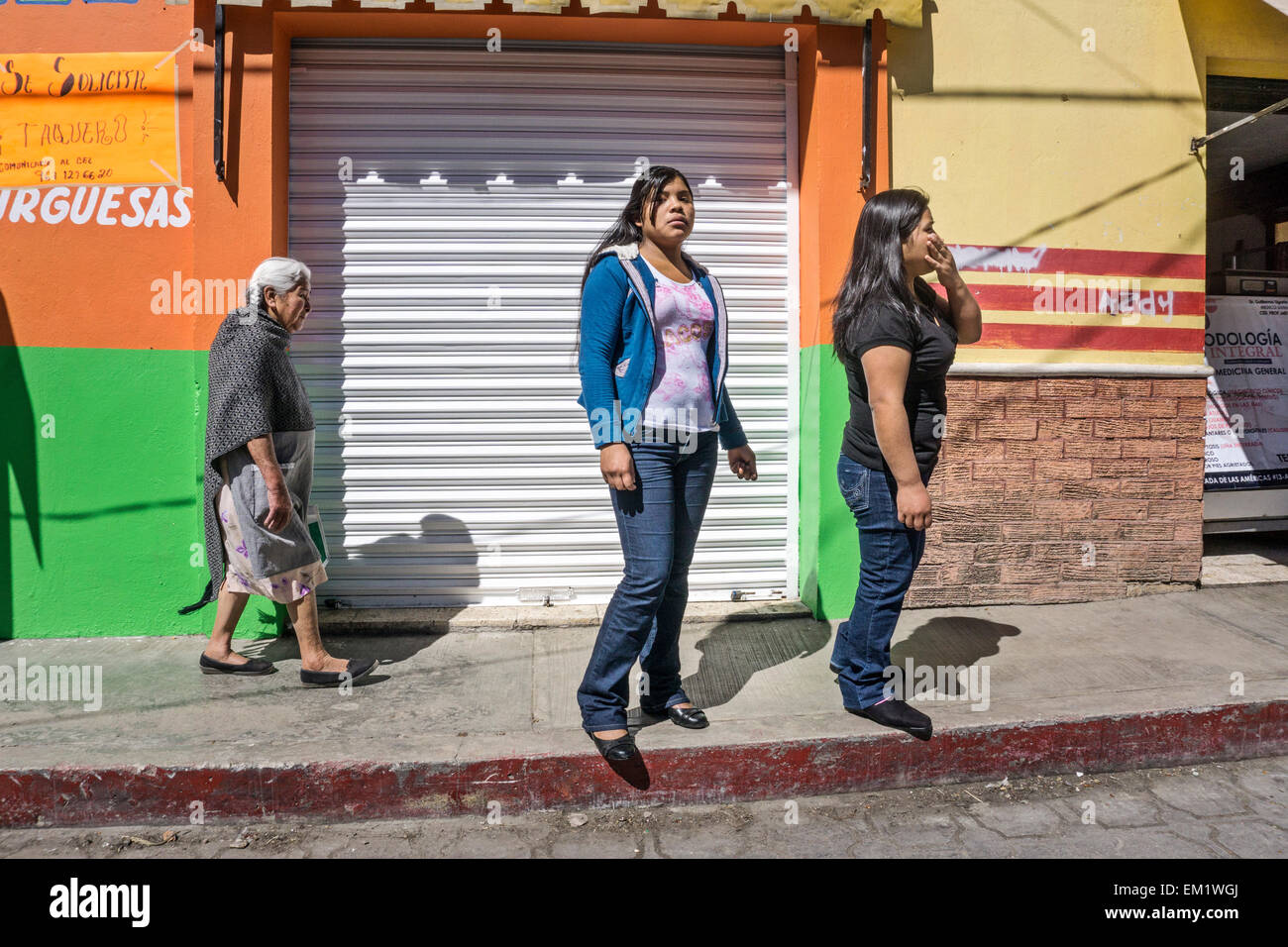 Les vieux digne femme indienne mexicaine est un contraste avec 2 adolescents indiens portant des jeans serrés San Cristobal de las Casas Banque D'Images