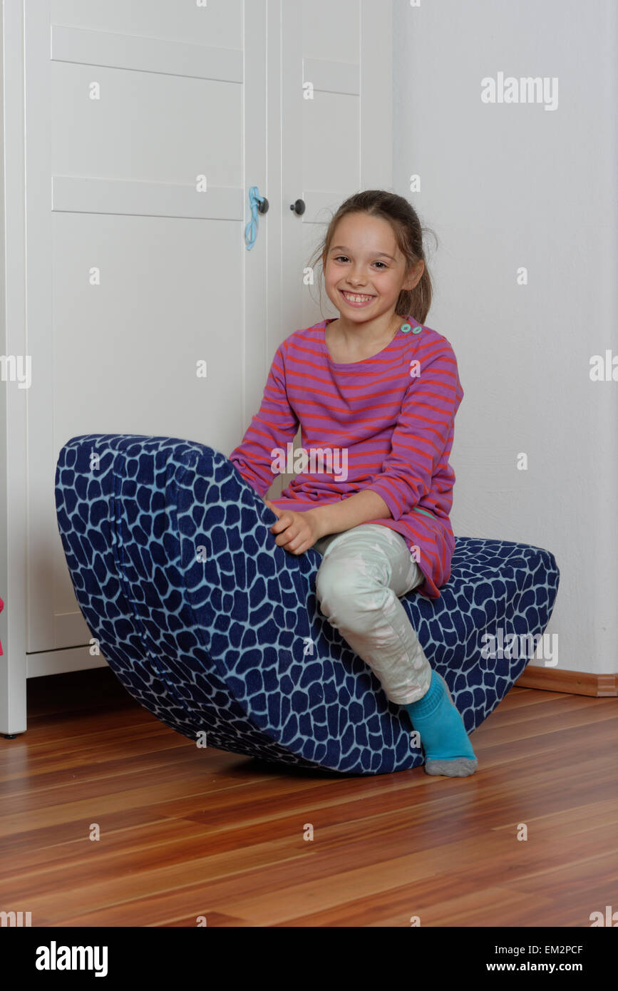Jeune fille sur une chaise à bascule de l'enfant, salle de jeux, Allemagne Banque D'Images