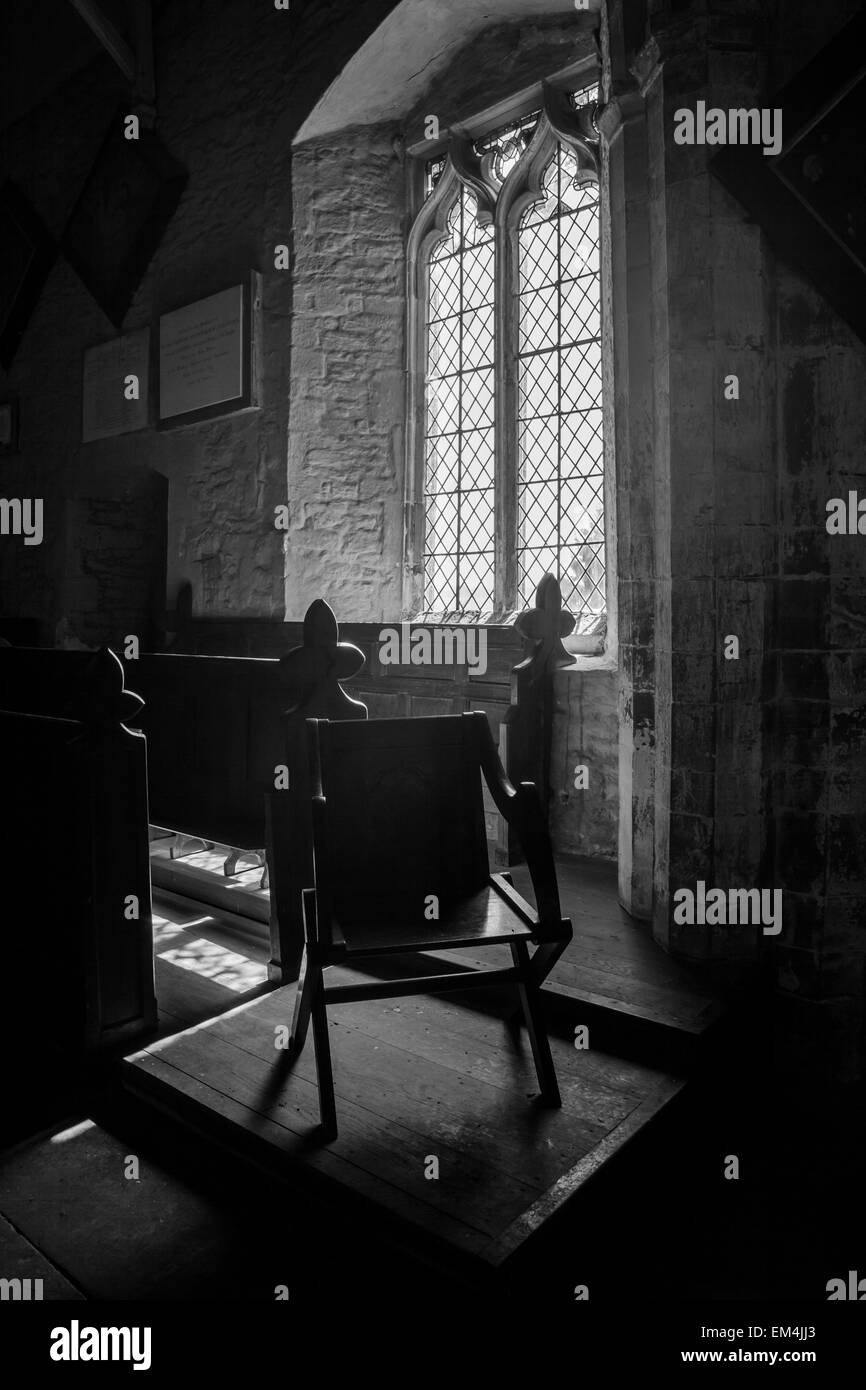 Une chaise à côté de quelques bancs et d'une fenêtre à l'intérieur de l'église St Barthélemy au Richard's Castle, Herefordshire Banque D'Images