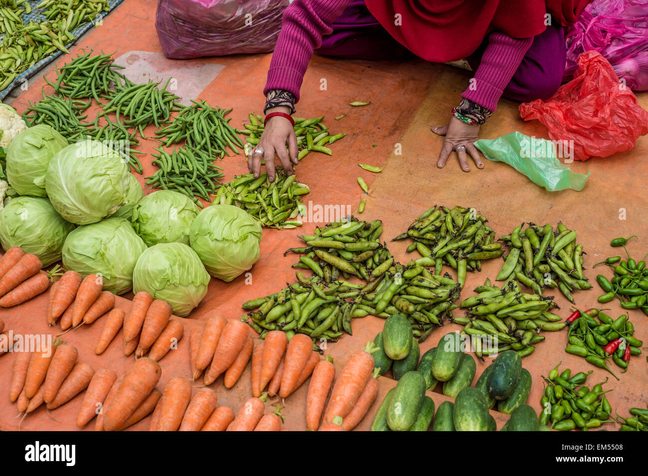 Une femme dans le tri vergetables au marché local Banque D'Images