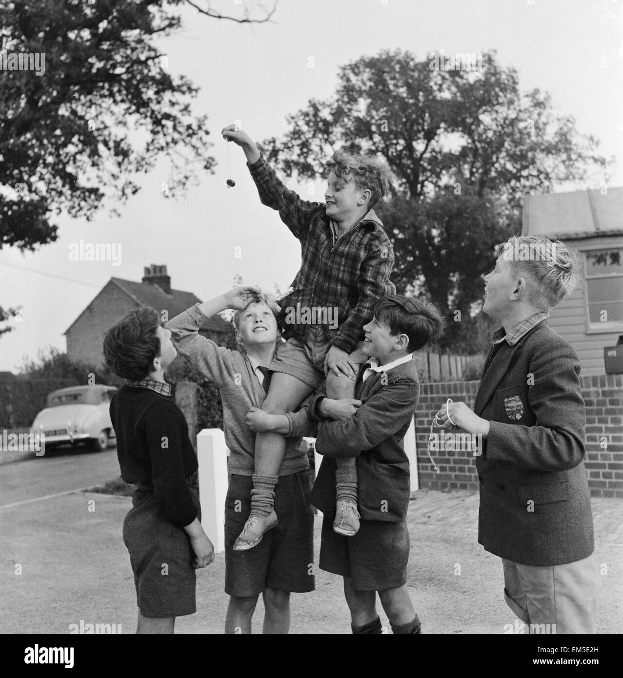 Un groupe d'amis qui participent à un jeu de l'extérieur de leur maison. conkers Septembre 1950. Banque D'Images