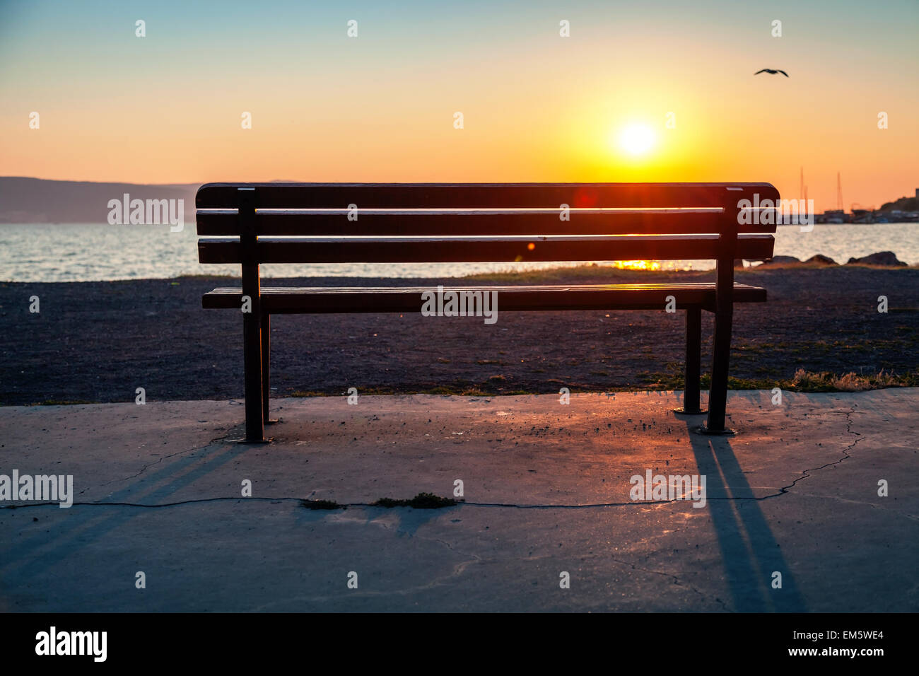 Banc vide en plein air sur un littoral avec shining soleil matinal sur un arrière-plan, tons vintage photo, avec effet lens flare Banque D'Images