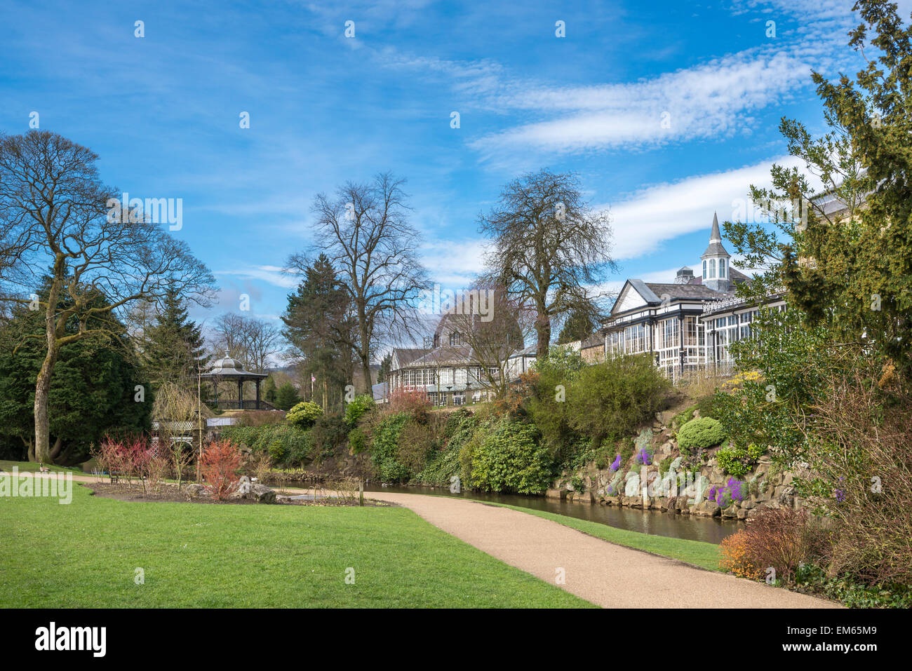 Les jardins du Pavillon Buxton, Derbyshire, Angleterre. Un chemin à côté du ruisseau et une vue sur les bâtiments victoriens. Banque D'Images