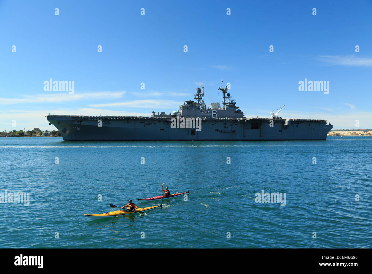Une photographie de de deux kayakistes dans l'avant de l'USS America (LHA-6), dans la baie de San Diego, comme vu de Seaport Village. Banque D'Images