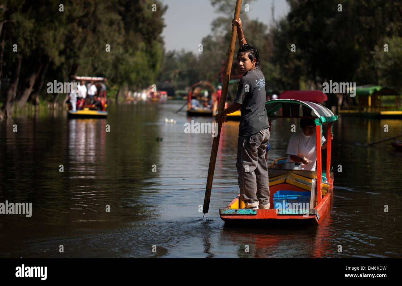 Un garçon utilise un poteau pour naviguer son bateau à travers le canal de Xochimilco, au sud de la ville de Mexico Banque D'Images