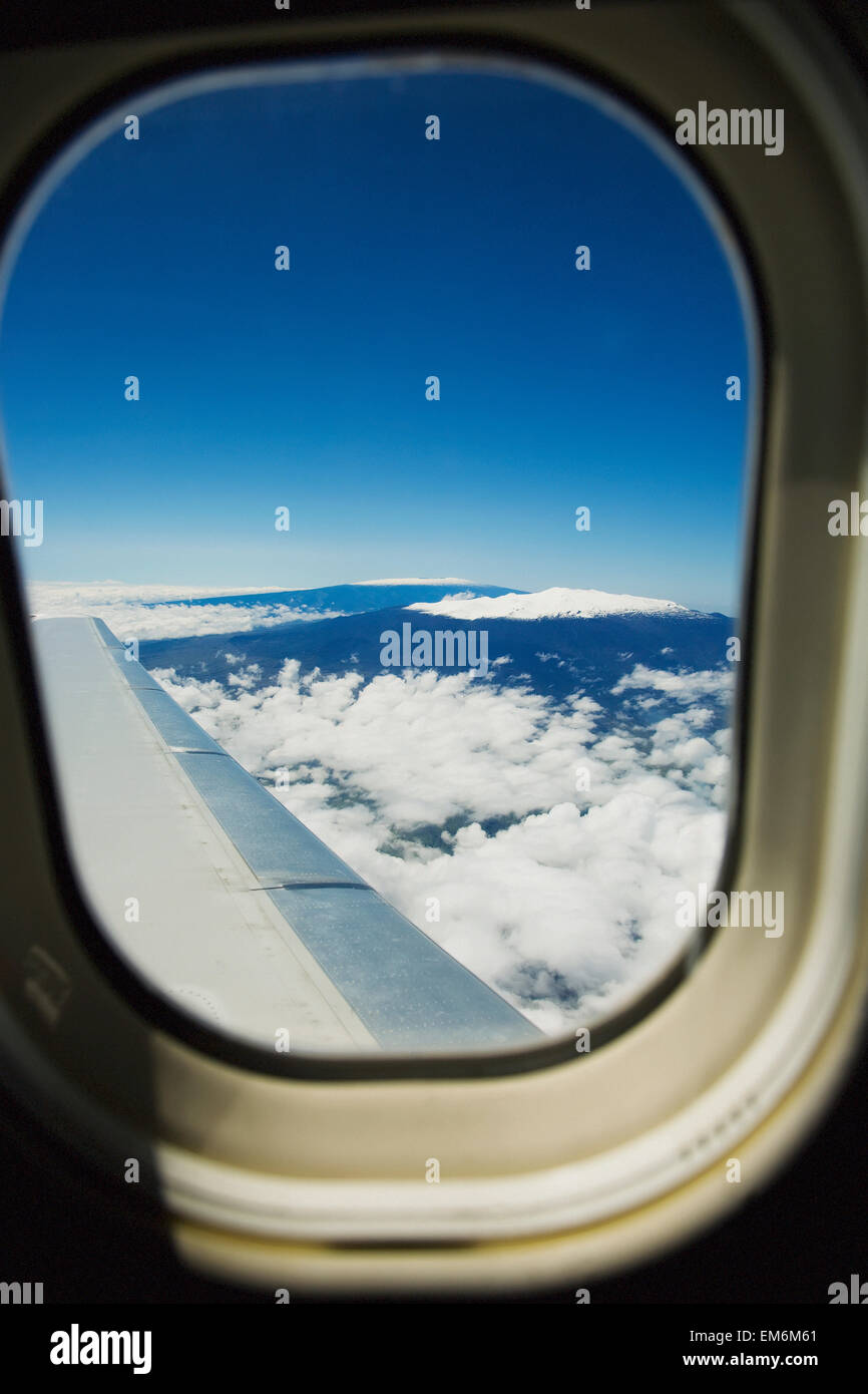 Hawaii, Big Island, vue aérienne du Mauna Kea et Mauna Loa couvertes de neige à travers la fenêtre d'un avion. Banque D'Images