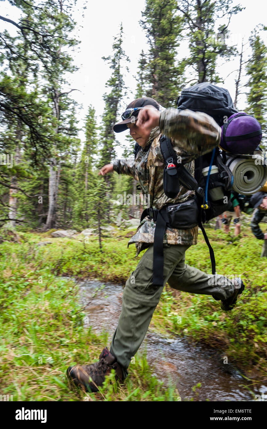 Les garçons aller à travers un ruisseau au cours d'un voyage à travers le sac à dos High Uintas Wilderness Area, Utah, gamme Uintas Banque D'Images