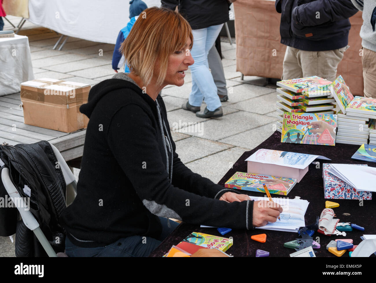Donner une démonstration de l'art de l'artiste assis à une table couverte de matériaux d'art Banque D'Images
