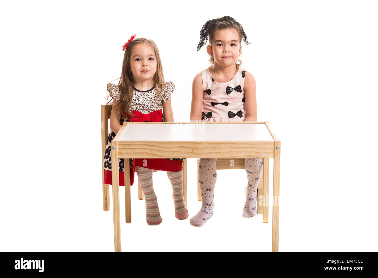 Deux filles assis sur des chaises à la table et faire wry bouche ensemble isolé sur fond blanc Banque D'Images