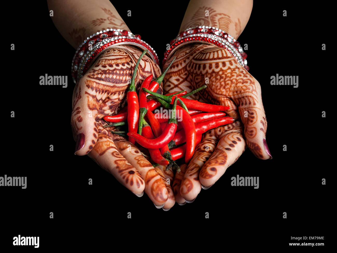 La main de femme henna holding red chili isolé sur fond noir avec le chemin de détourage Banque D'Images