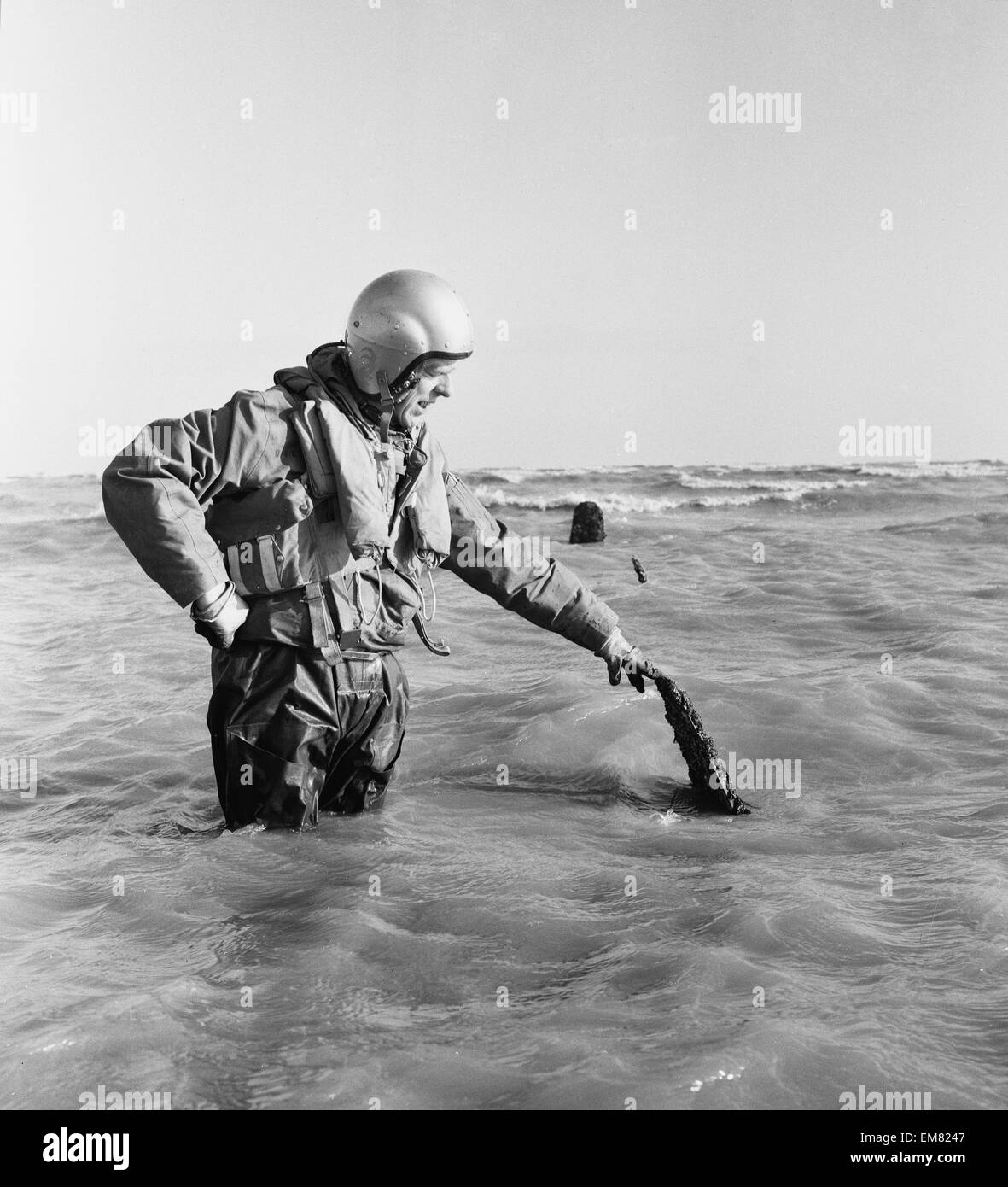 Navigateur maître Colin Walsh de la RAF Air Sea Rescue Service est à la hauteur de la taille dans l'eau sur un banc de sables bitumineux à Goodwin, tout près de la côte de Ramsgate, suite à la découverte d'un bombardier Lancaster de la RAF qui n'a pas réussi à rendre à la maison de sa mission dans la seconde guerre mondiale. Les hommes de la RAF au service de sauvetage dans le Kent Manston numérisation continuellement les mers et repéré les trois hélices sortant de l'eau, ce qui les conduit à examiner de plus près. 6e février 1964. Banque D'Images