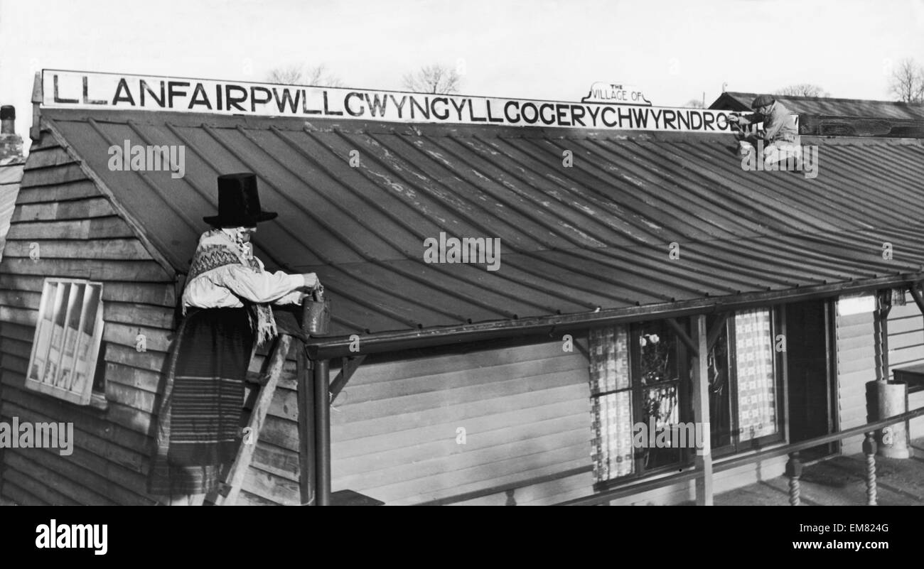 M. et Mme Jones de Llanfairpwllgwyngyllgogerychwyrndrobwllllantysiliogogogoch sur l'île d'Anglesey, dans le Nord du Pays de Galles peindre un panneau portant le nom long de leur village au-dessus de leur boutique qui se préparent pour les visiteurs de Noël. Le 24 mars 1940. Banque D'Images