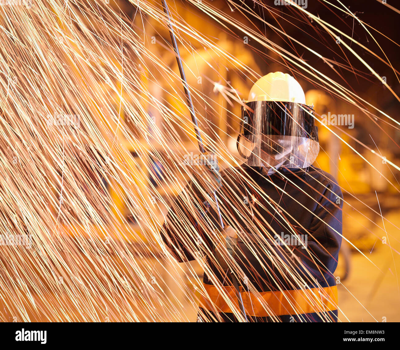 Steelworker holding sample lance des étincelles derrière dans les aciéries Banque D'Images