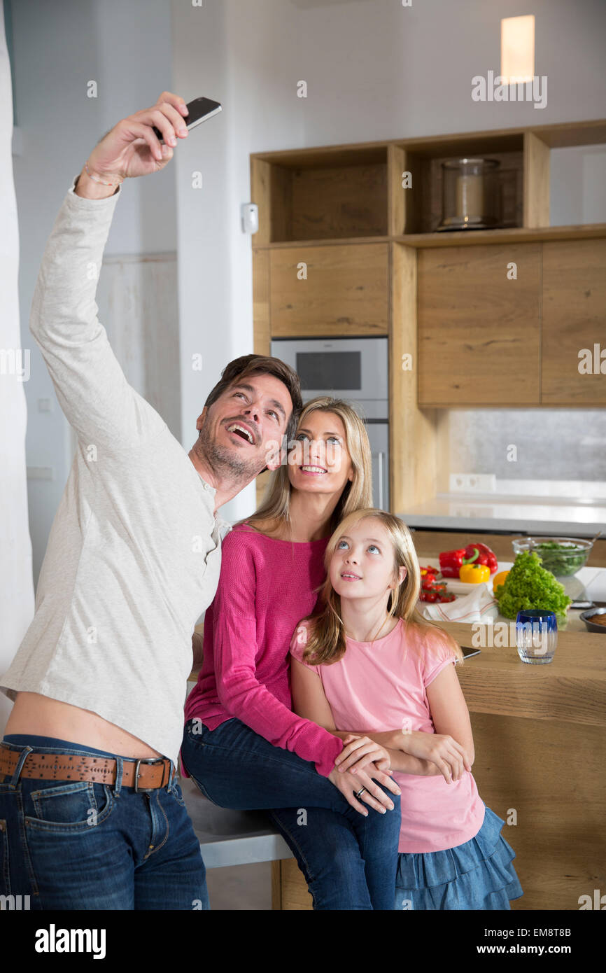 Young man holding up smartphone pour les selfies famille dans la salle à manger Banque D'Images