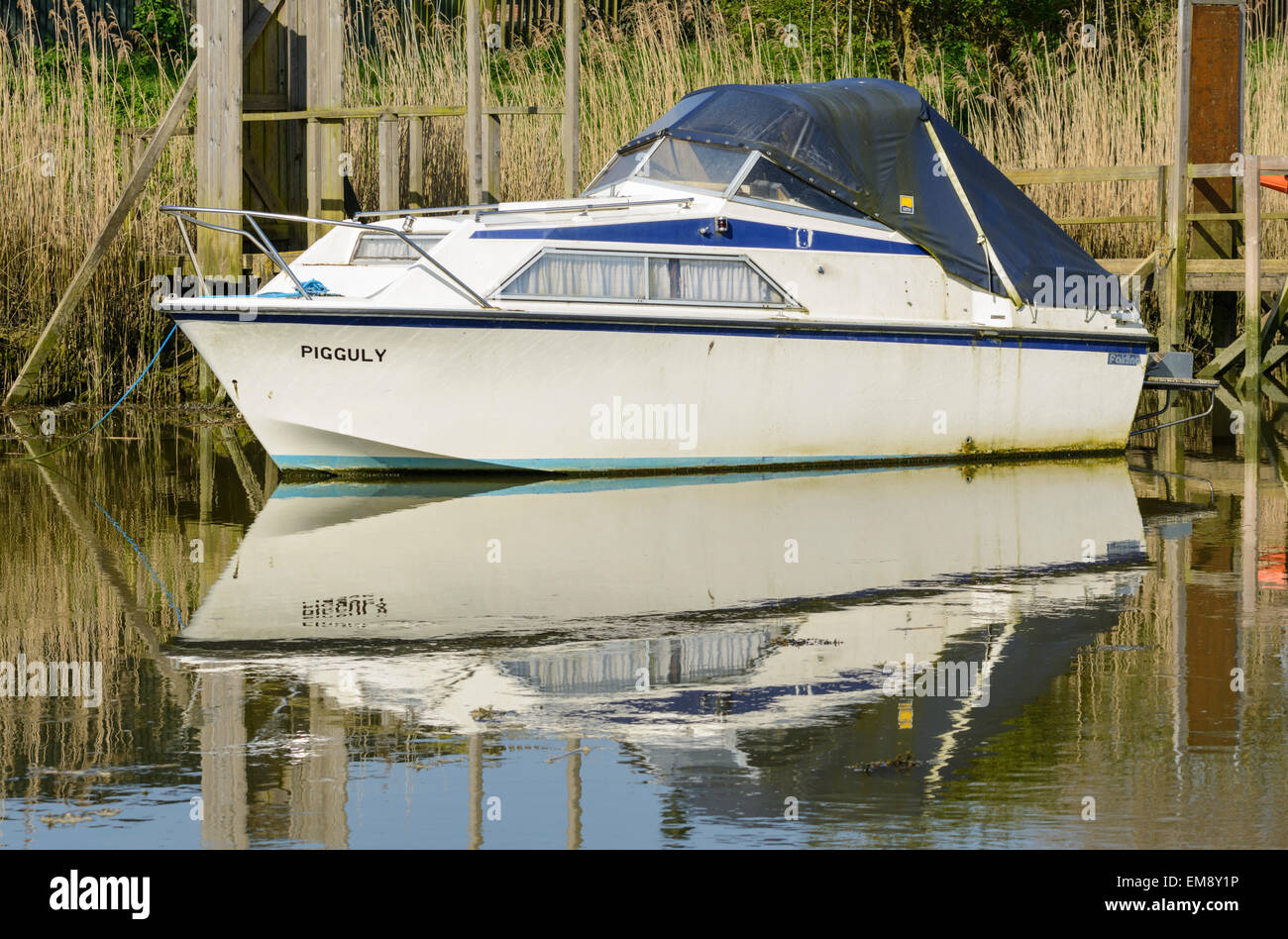 Petit bateau amarré sur une rivière avec son reflet dans l'eau. Banque D'Images