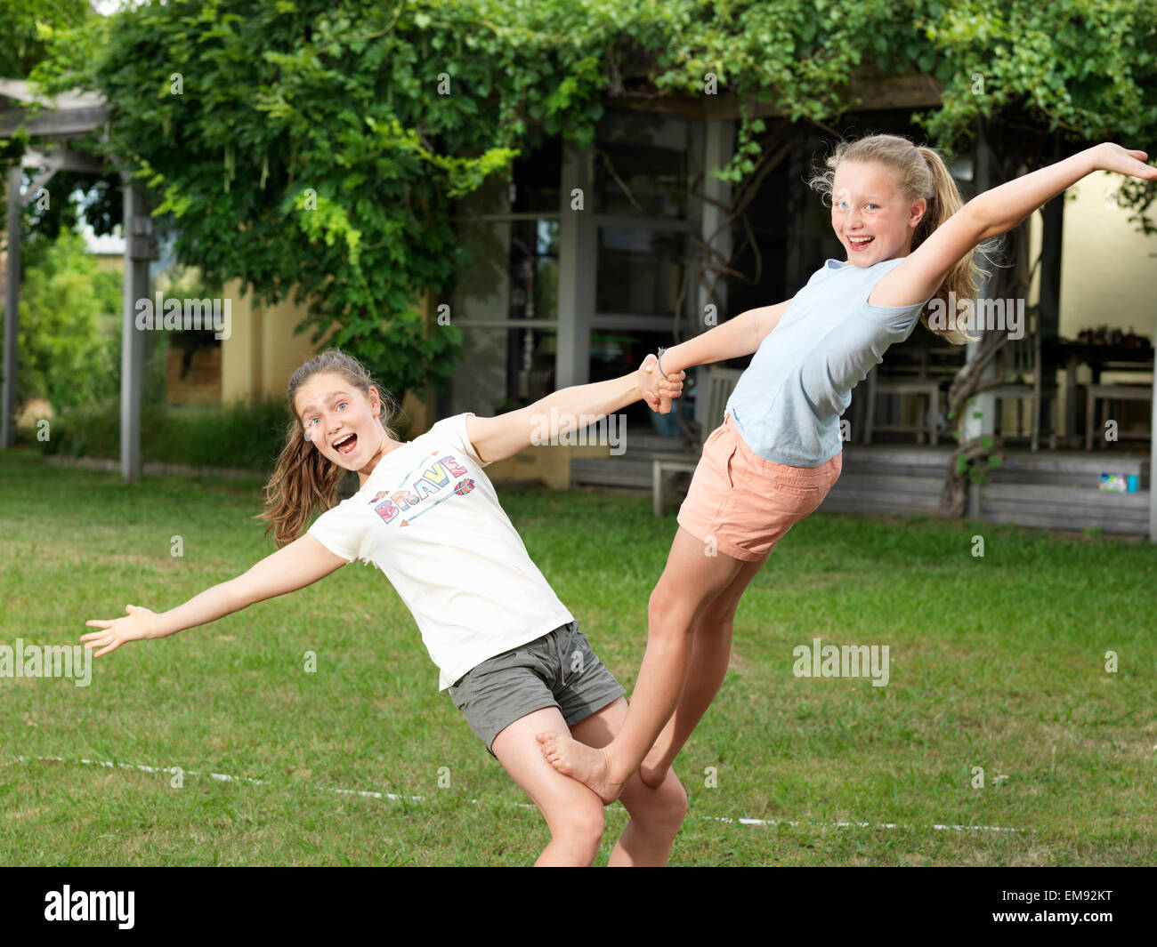 Deux sœurs faisant des acrobaties dans jardin Banque D'Images