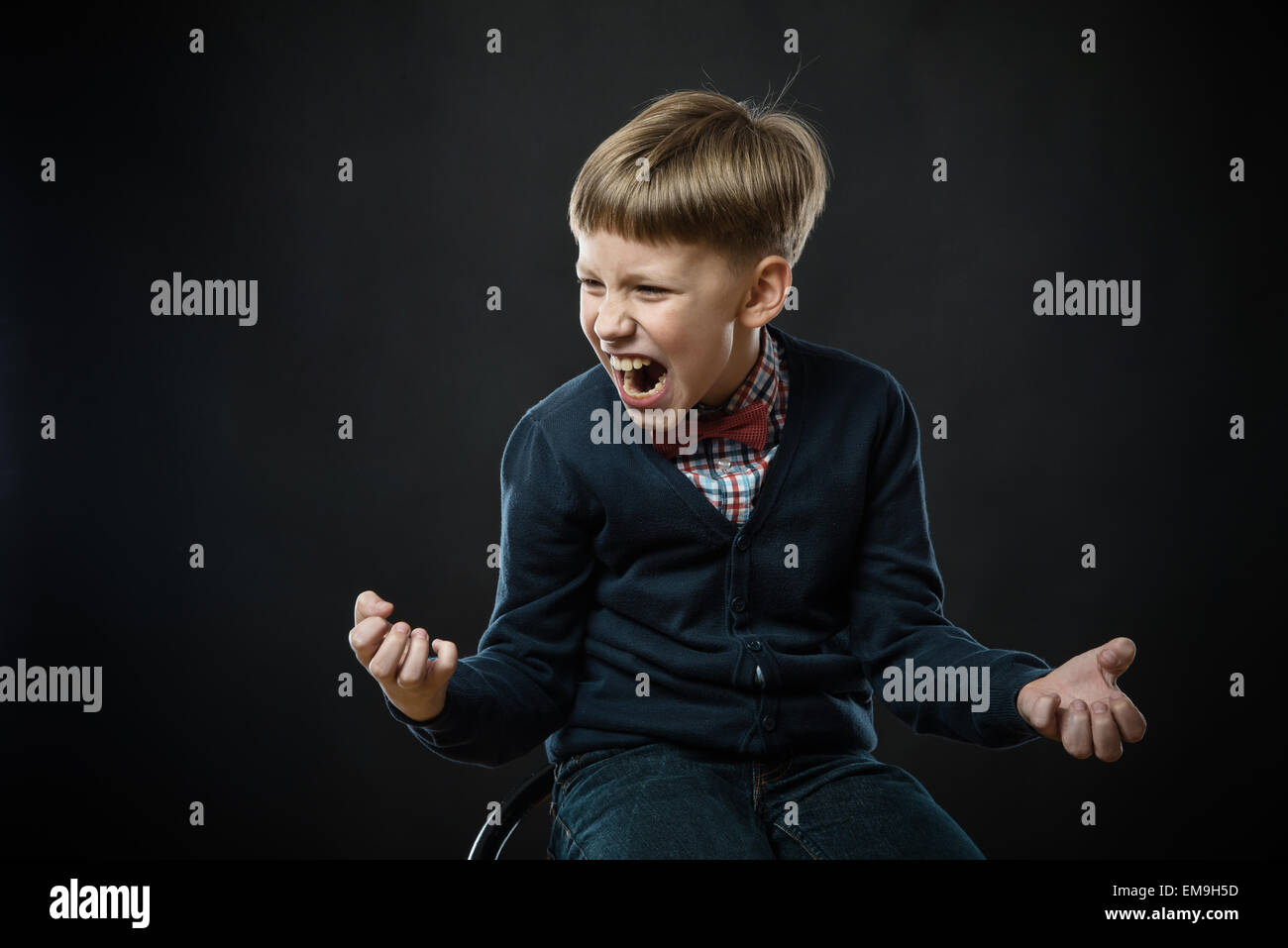 Garçon criant bruyamment. studio shot, fond noir Banque D'Images