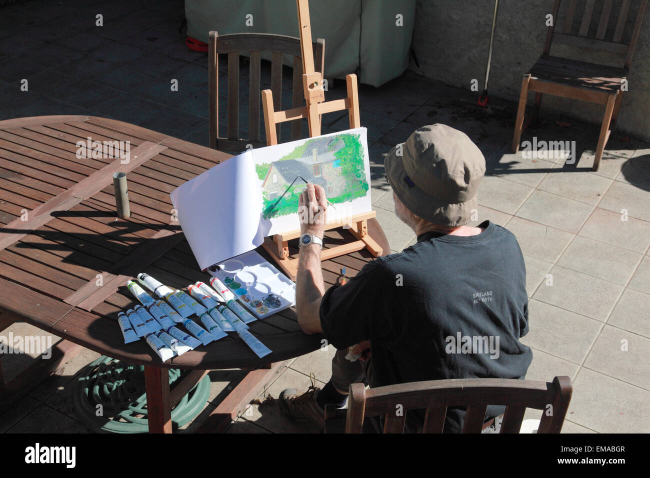 Un homme à la retraite par la peinture de détente au soleil dans un jardin en France Banque D'Images