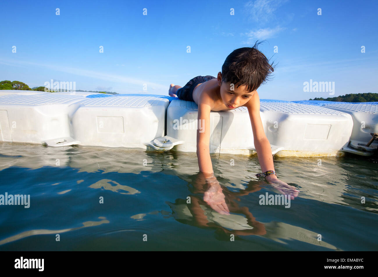 Jeune garçon jouant dans la mer sur une plate-forme flottante Banque D'Images