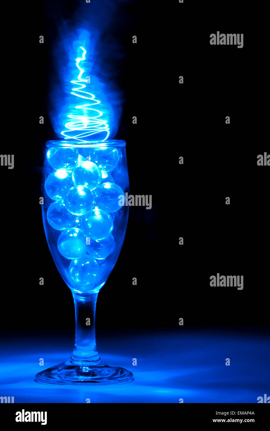 Marbres clairs dans un verre à vin avec lumière bleue peinture Banque D'Images