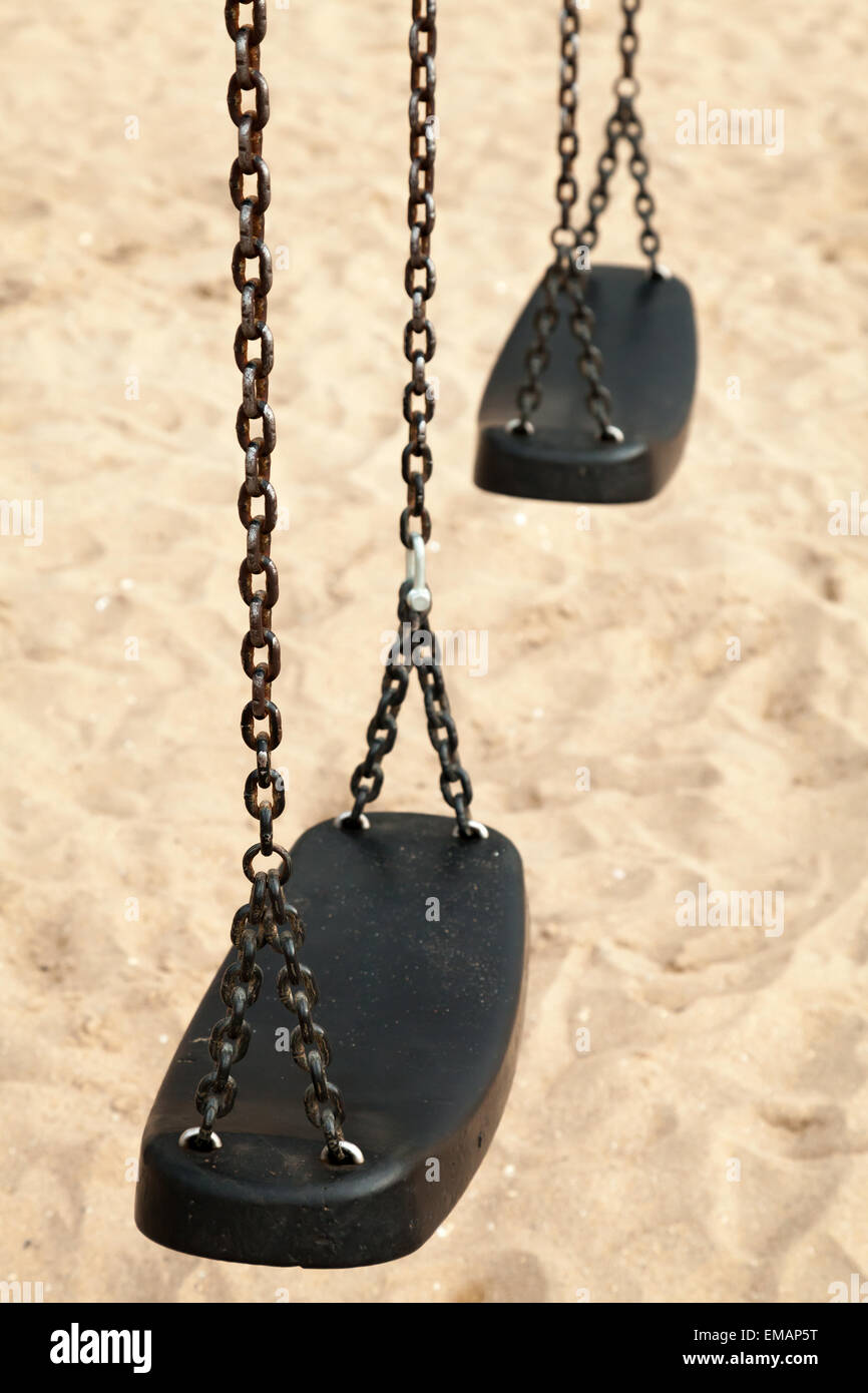 Balançoires vides en plastique noir et acier chaînes sur une plage de sable fin, photo gros plan avec mise au point sélective et peu profondes 6 Banque D'Images