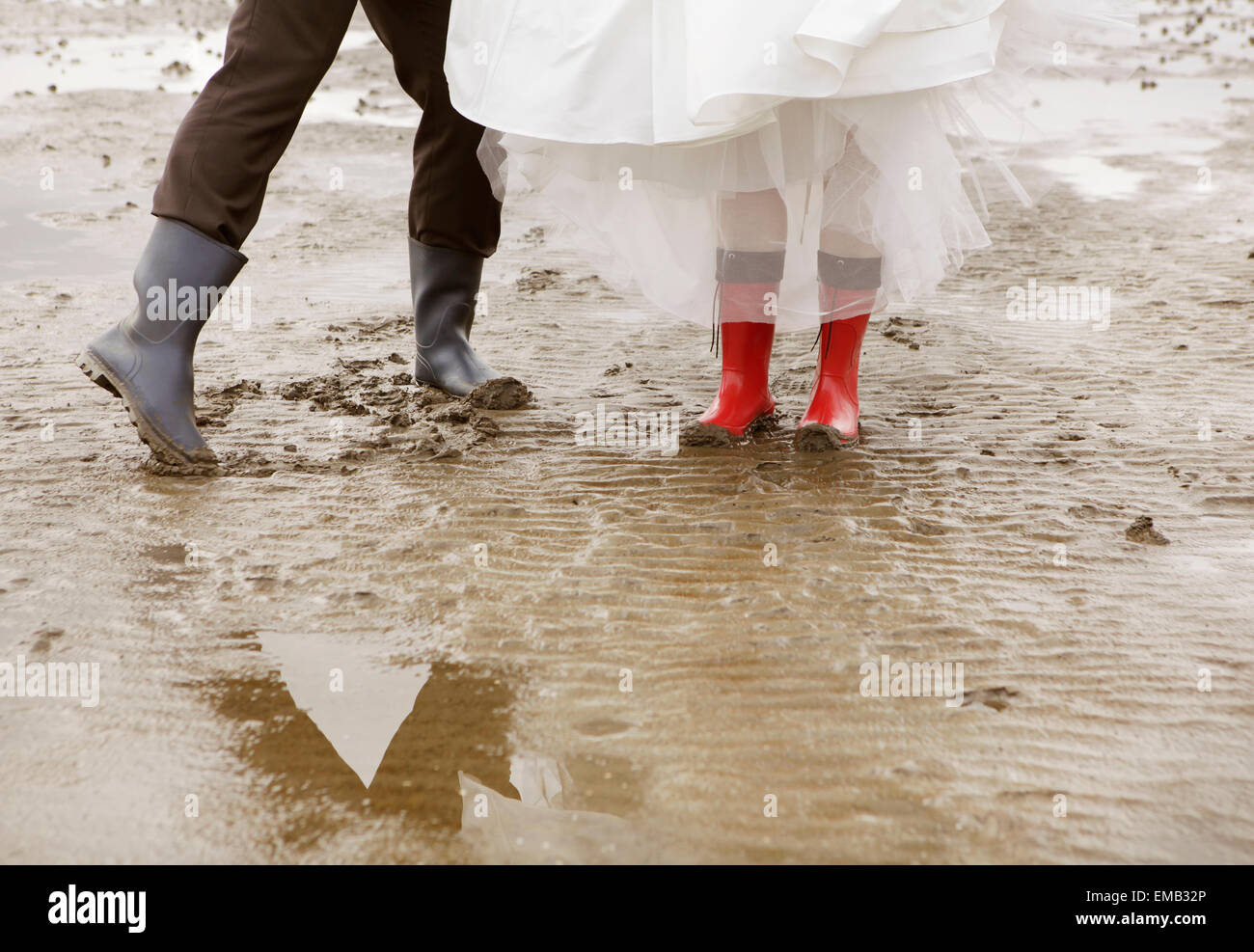 Un couple marié avec des bottes en caoutchouc et robe de mariage va pour une promenade dans la mer des Wadden Banque D'Images