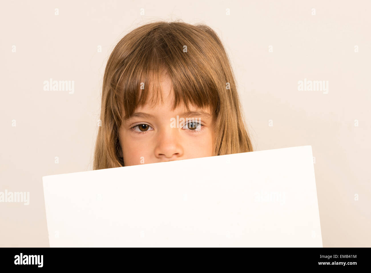 Petite fille portant un poster couvrant sa bouche Banque D'Images