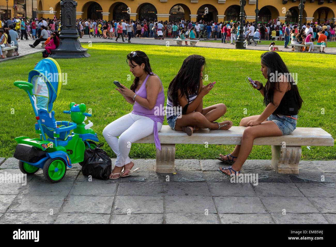 Pérou, Lima. Trois jeunes femmes contrôler leur téléphone cellulaire dans la Plaza de Armas. Banque D'Images