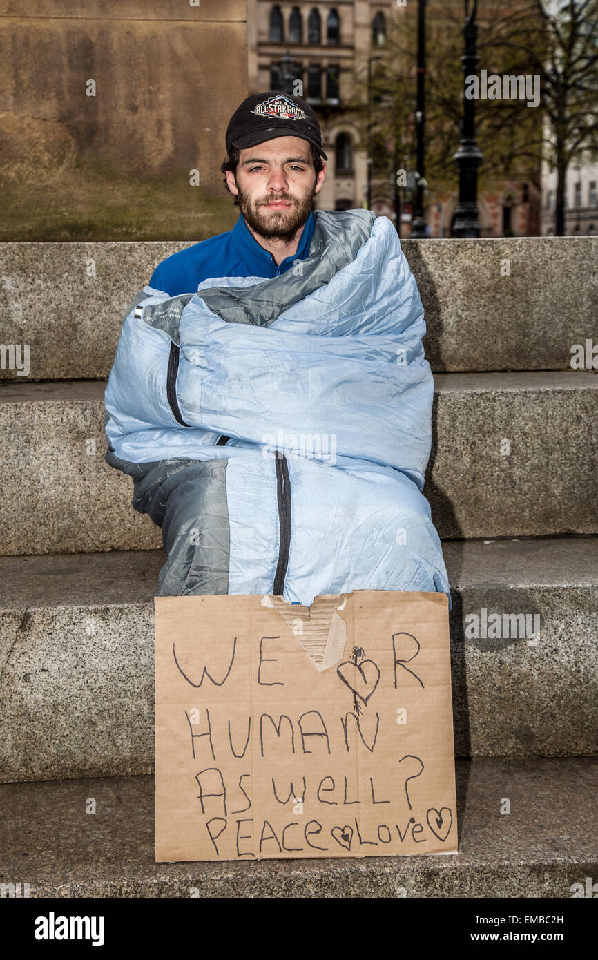 Panneau en carton, « nous sommes humains aussi bien » Manchester, Royaume-Uni avril 2015. Max Brown, 27 ans, de Nottingham alors que les militants pour les sans-abri continuent de faire un stand devant la mairie de Manchester pour sensibiliser à la crise du logement temporaire. Les manifestants dorment dans des tentes dans un campement à Albert Square ; beaucoup ont récemment été libérés de prison et n'ont aucun espoir de logement. Le groupe, appelé Homeless Rights of Justice, comparaîtra devant le tribunal lundi pour être expulsé, après quoi ils auront 48 heures pour partir. Banque D'Images