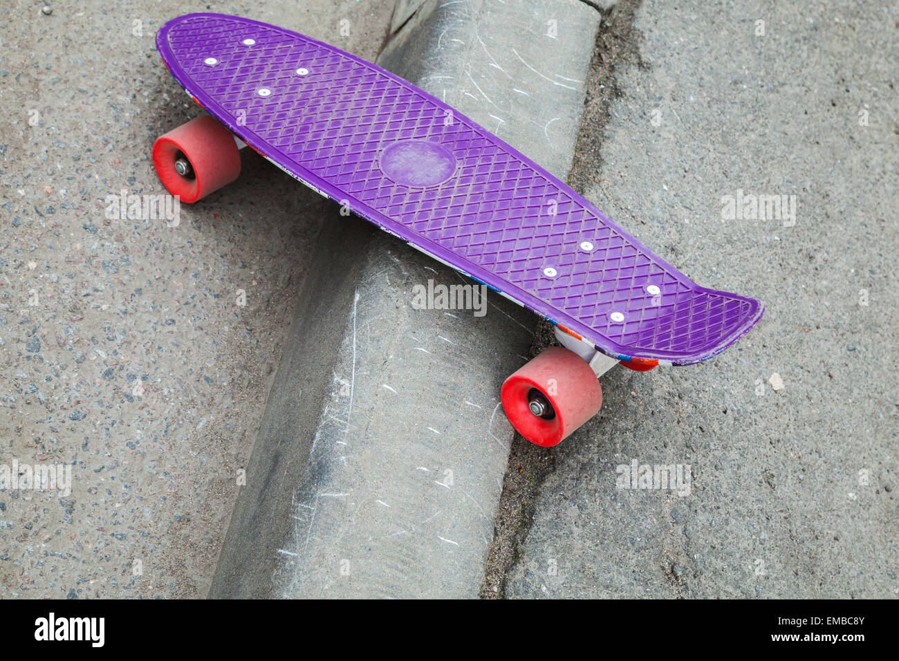 Skateboard moderne se trouve sur la bordure de la route d'asphalte Banque D'Images