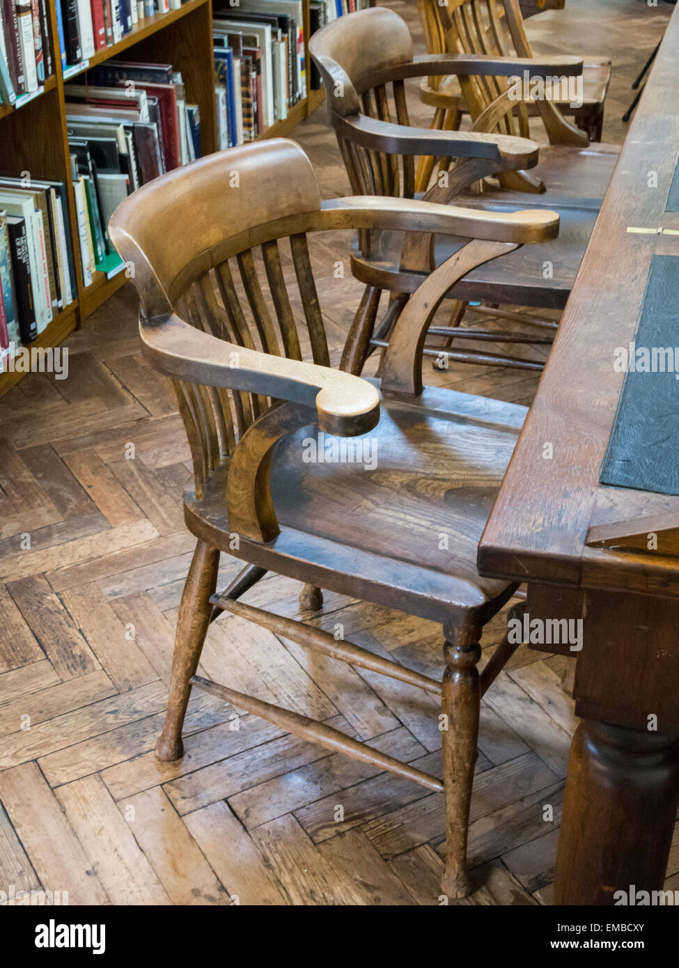 Des chaises en bois au sol en bois d'un bureau avec chaises derrière eux dans la bibliothèque centrale de Bristol. Banque D'Images