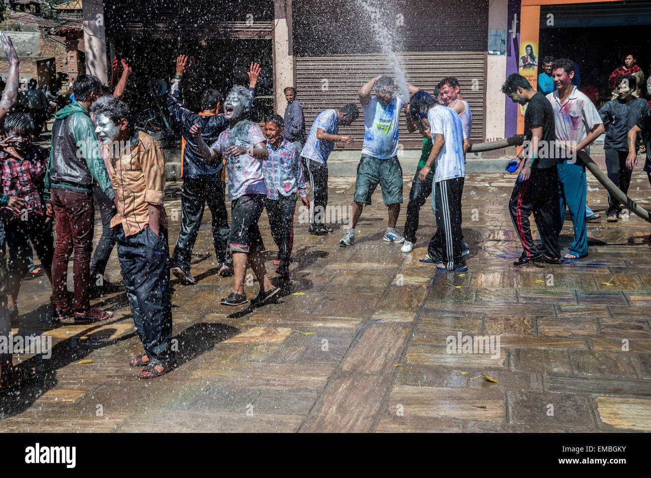 Un groupe d'adolescents est mouillé à l'aide d'un flexible à Katmandu, au cours du festival holi Banque D'Images