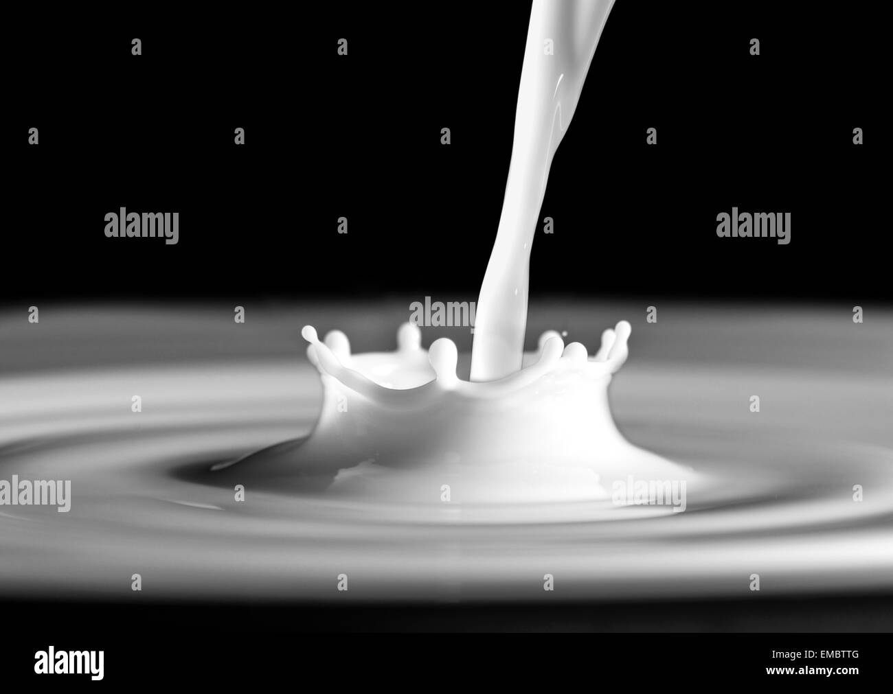 Splash de lait et goutte de lait sur fond noir Banque D'Images