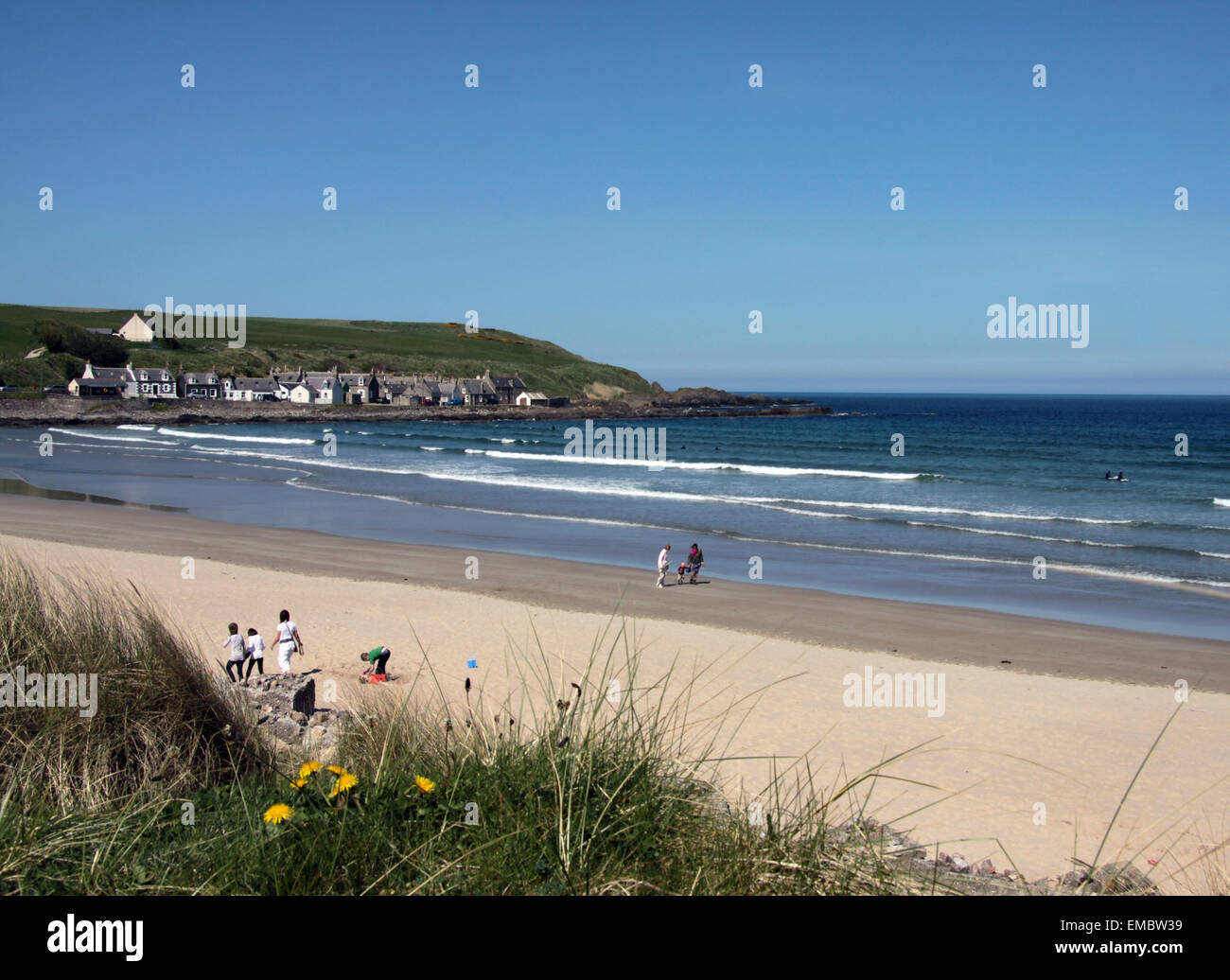 La plage d'or de Sandend Bay avec des gens de la distance s'amusant et l'océan bleu Banque D'Images