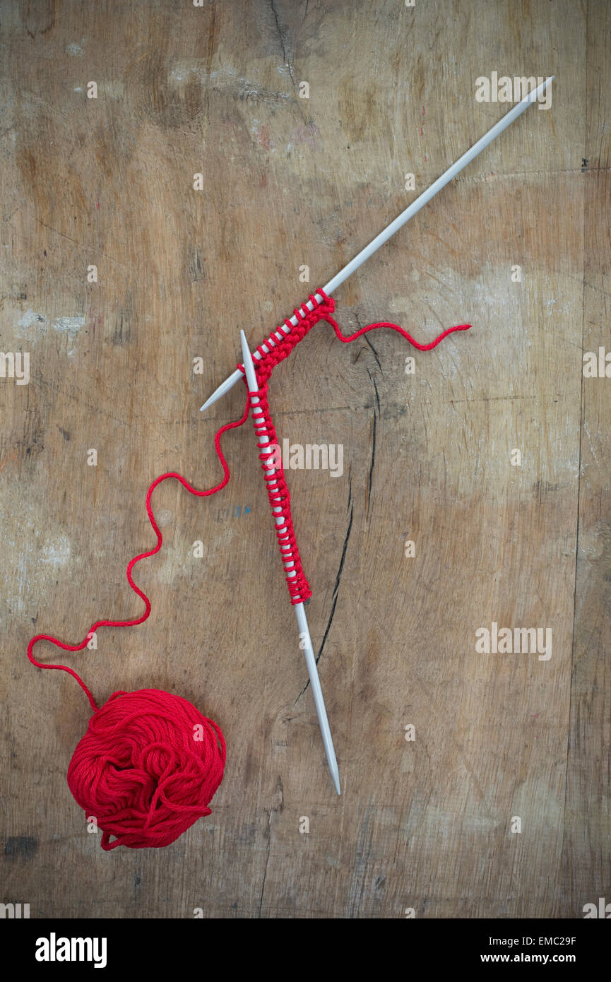 Pelote de laine rouge et le tricotage sur bois Banque D'Images