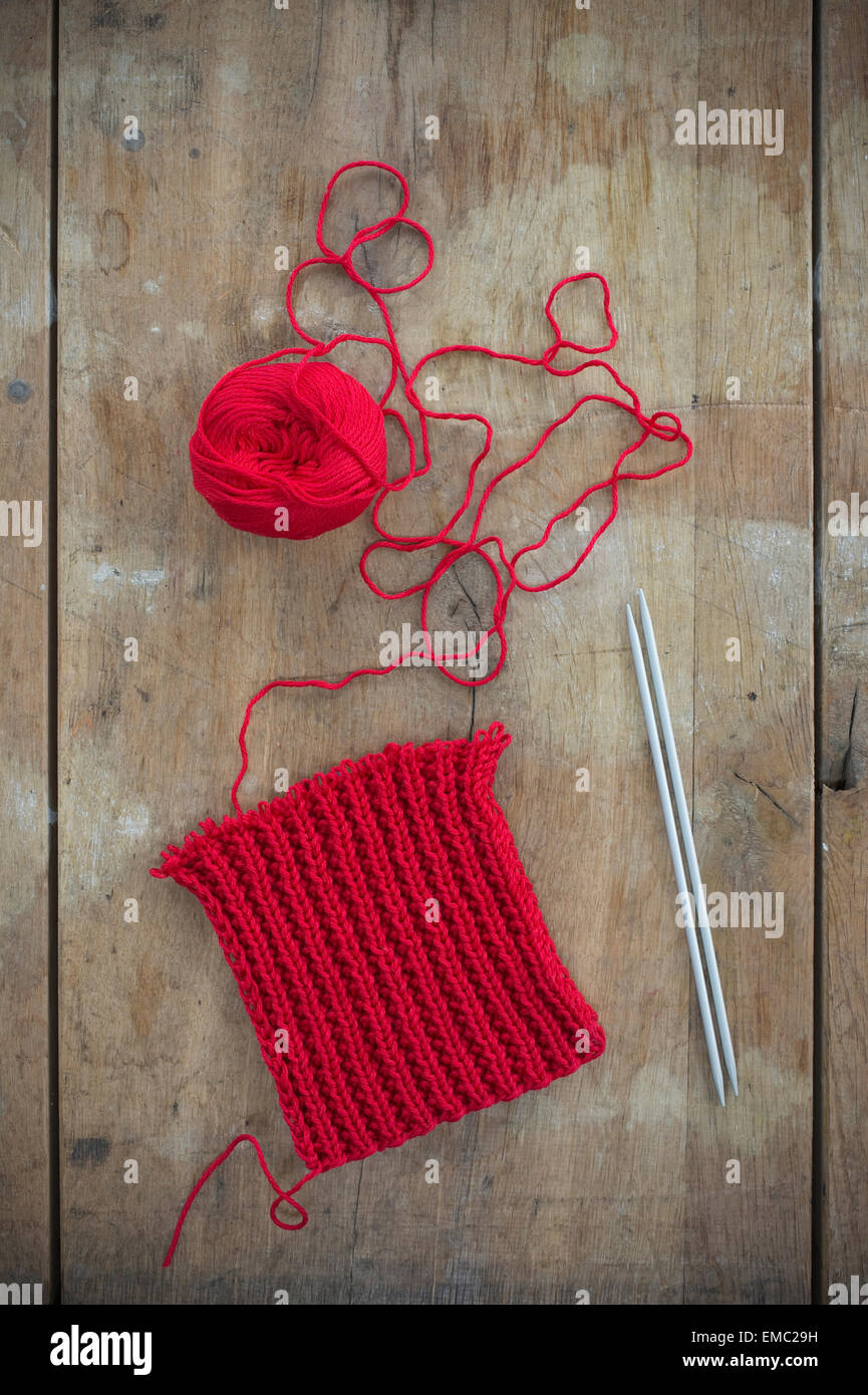 Pelote de laine rouge et le tricotage sur bois Banque D'Images