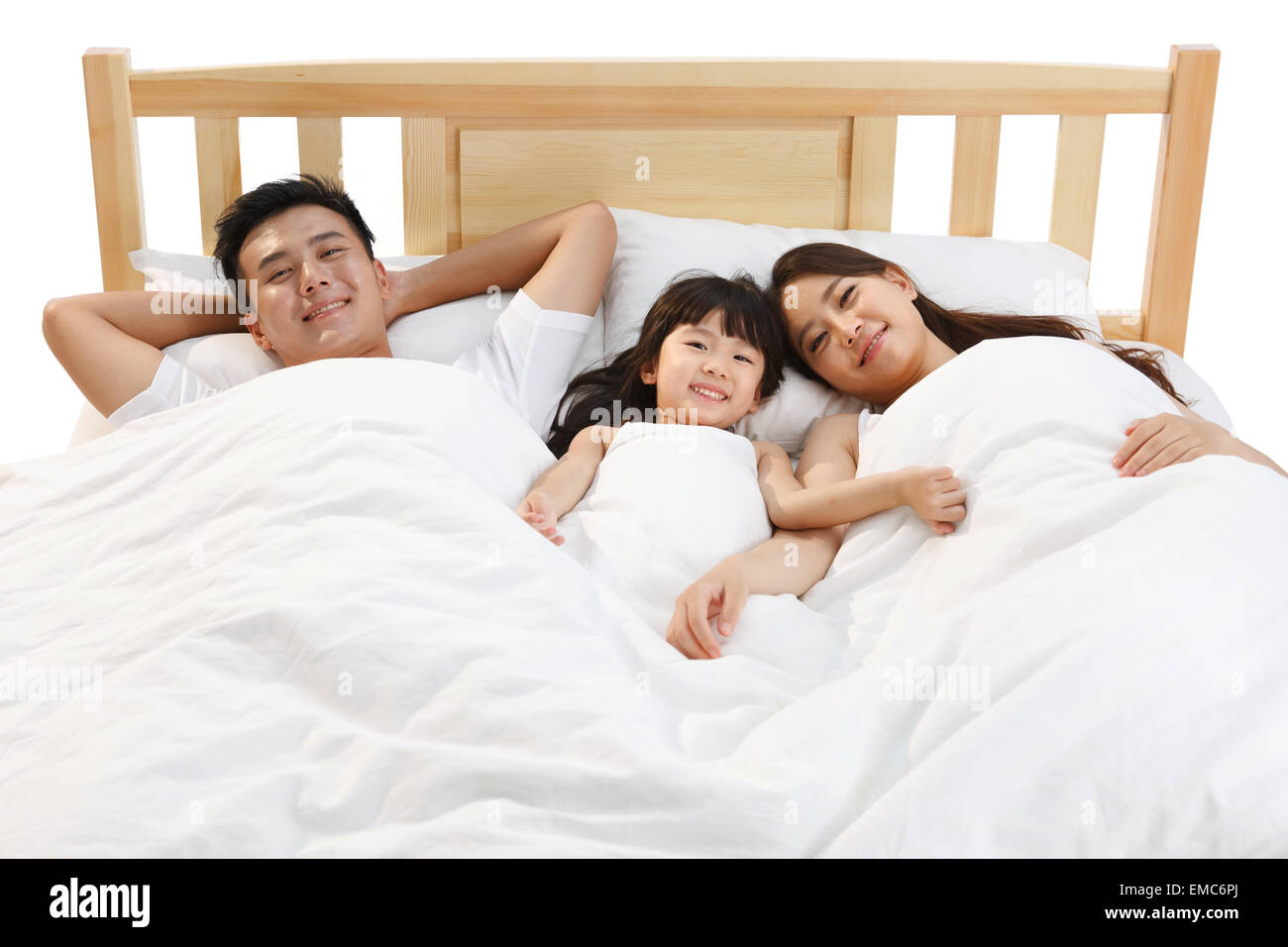 Une famille de trois s'assit sur le lit dans la chambre à coucher Banque D'Images