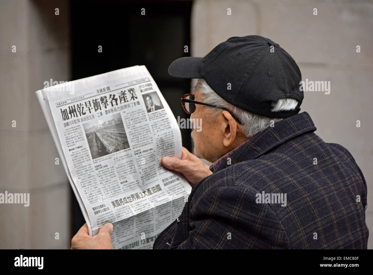 Un Américain chinois Senior citizen la lecture d'un journal chinois dans Columbus Park dans le quartier chinois, Manhattan, New York. Banque D'Images